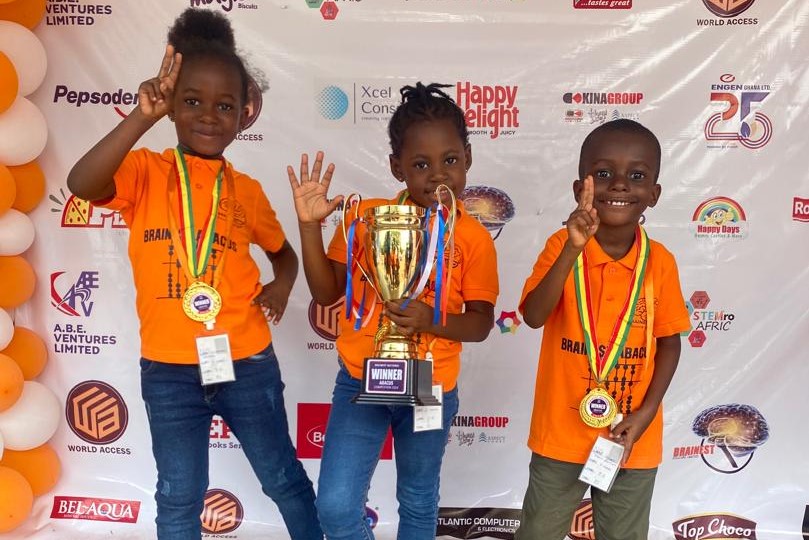 three students with a trophy and medals