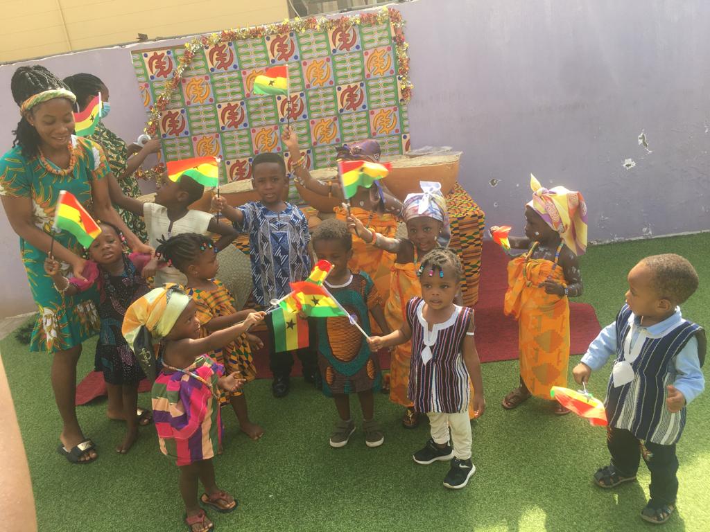 children in african wear holding Ghana flags